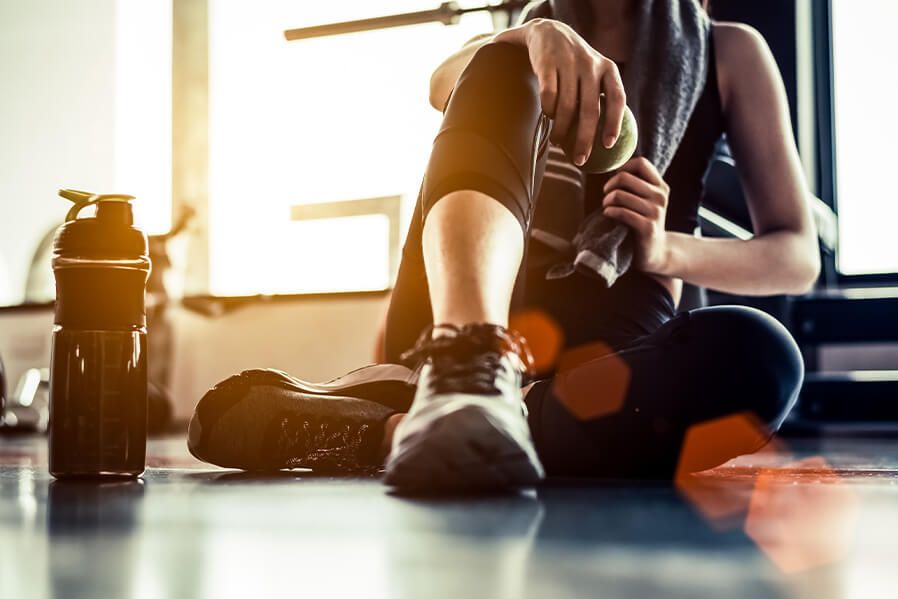 Frau sitzt in Sportkleidung am Boden