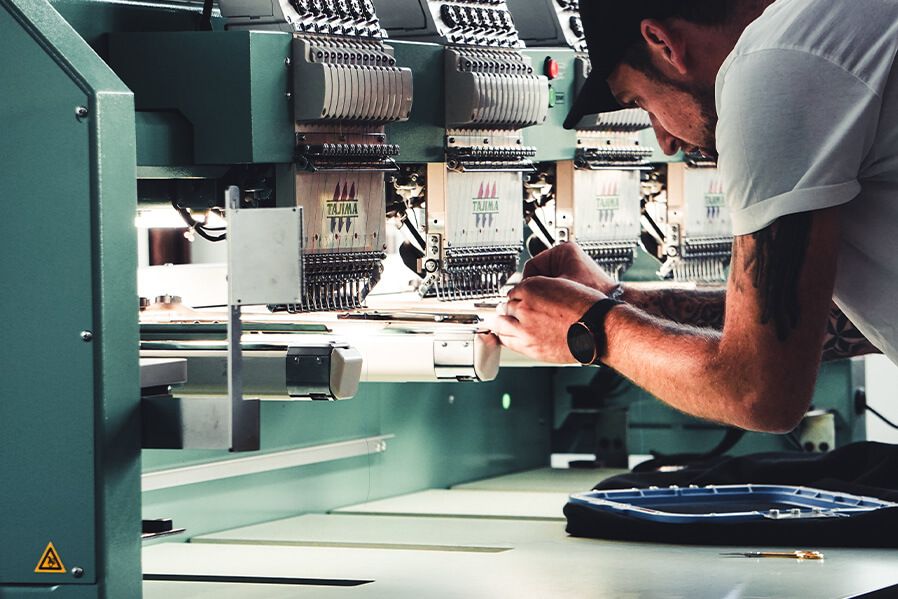 Markus von mictex fädelt Faden in die Stickmaschine ein